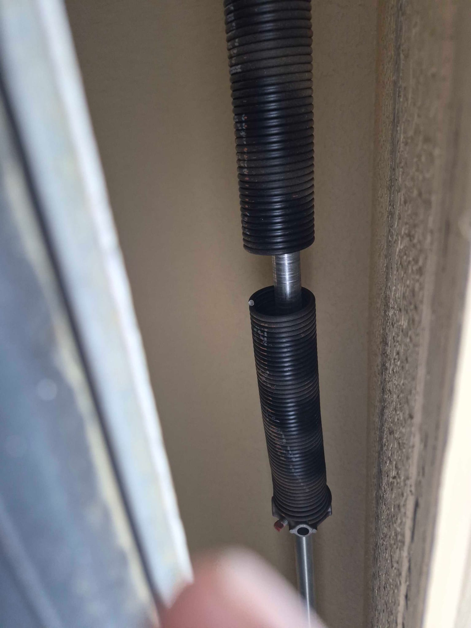 A broken black torsion spring on a garage door shaft, in Johnson City
