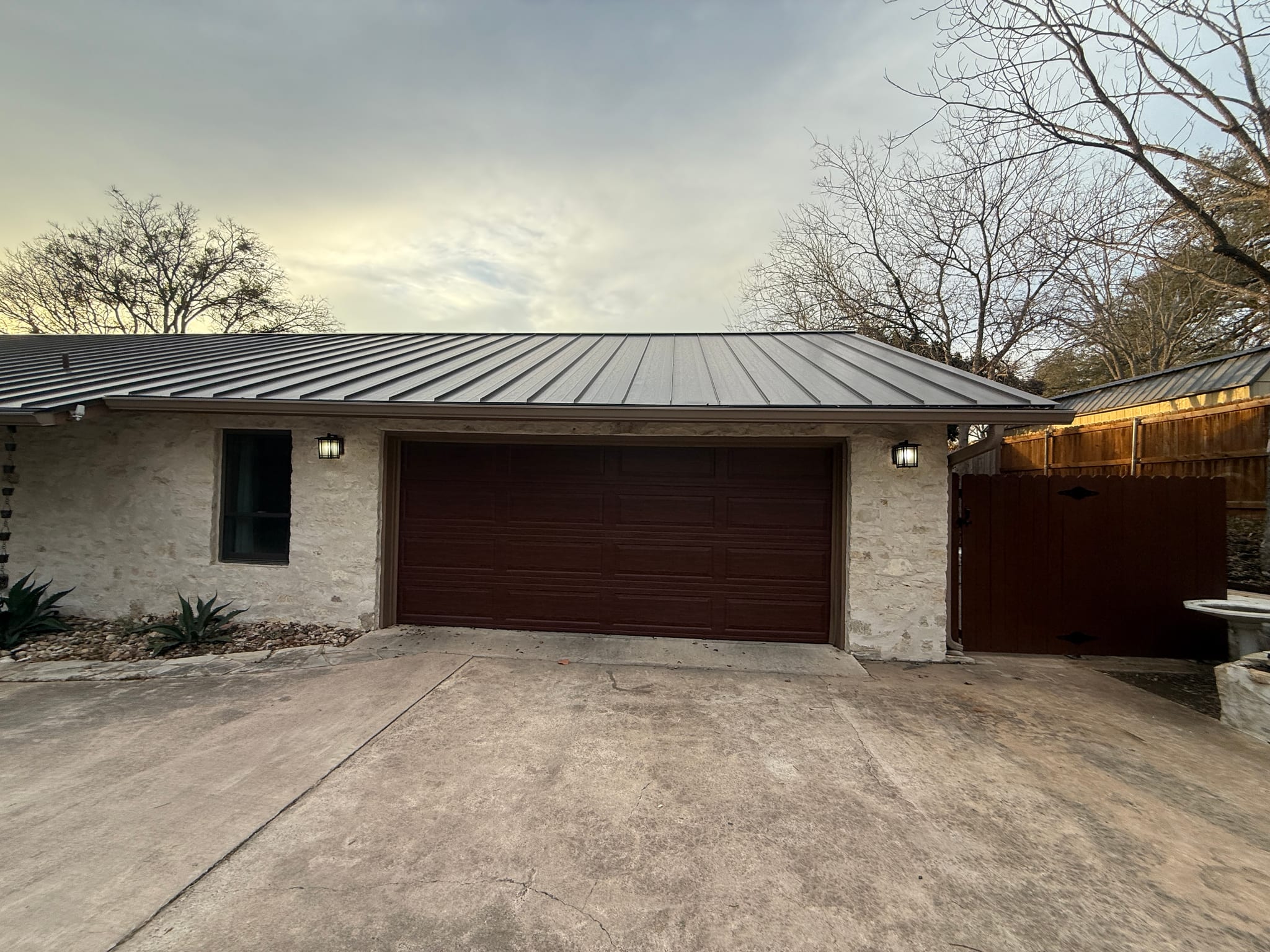A dark wood finish double garage door installed on a stone house