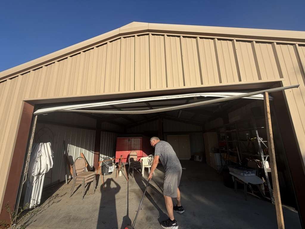 Technician adjusting a bent garage door track and section inside a metal building in Marble Falls